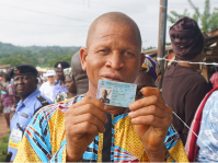 A person with albinism showcasing his voters card after casting his vote